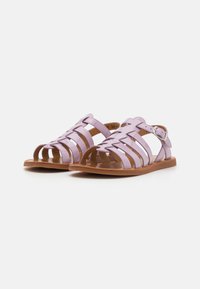 Lilla PVC-sandaler med vevde stropper og en brun såle. Justerbar ankelstropp med metallspenne og åpen tå-design. Flat stil.