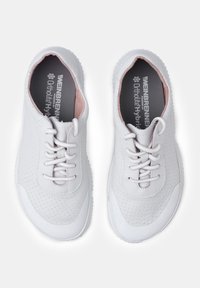 White leather sneakers with perforated upper, pink accents, and white rubber sole. Features laces and cushioned insole. Classic sporty design.