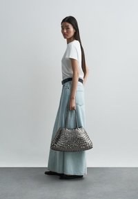 Πλεκτή γκρί τσάντα με διπλές λαβές, σε συνδυασμό με λευκό μπλουζάκι και ανοιχτόχρωμη τζιν φούστα. Λείο άγγιγμα και δομημένη σιλουέτα.