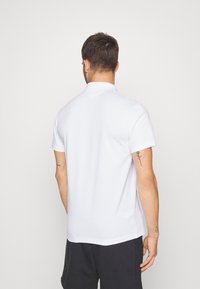Witte polo shirt van gladde stof, met een klassieke kraag, korte mouwen en een relaxed fit. Geen zichtbare patronen of logo's.