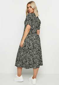 Svartvit blommig mönstrad midiklänning med korta puffärmar och en avslappnad passform. Matchad med vita platåskor.