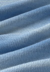 Tissu tricoté bleu clair avec texture côtelée visible et plis doux créant des ombres délicates.
