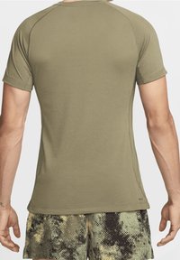 Oliivinvihreä lyhythihainen urheilupaita, jossa on sileä pinta, raglan-hihat ja verkkopuolelliset paneelit hengittävyyden lisäämiseksi.