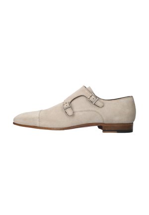Licht beige suède nette schoenen met een spits toelopende neus, dubbele zilveren gespdetails en een lage houten hak, met een gladde textuur.