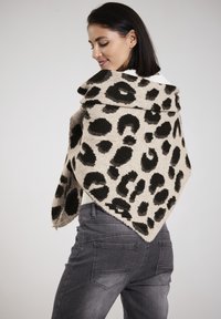 Leopard-patterned shawl in beige and black, soft texture, draped over shoulders, with a pointed hem and rolled collar, matched with gray jeans.