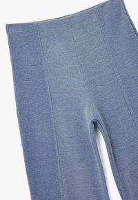 Niebieskie legginsy wykonane z miękkiego, elastycznego materiału. Posiadają wysoki stan i detale szwowe dla dopasowanego wyglądu. Gładka tekstura na całej powierzchni.