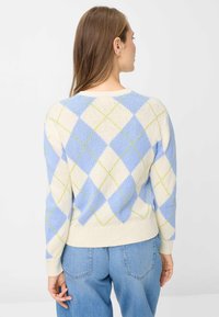 Maglione lavorato a maglia con sfondo crema e motivi a rombi blu e verdi. Polsini e bordo a coste, vestibilità morbida e scollo rotondo.