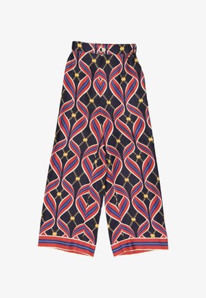 Pantalon à jambes larges avec base bleu marine, rayures ondulées rouges, blanches et bleues, motif chaîne dorée, fermeture par bouton et poignets rayés.