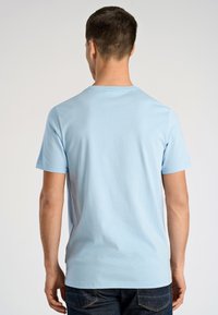 Maglietta di cotone azzurro chiaro con maniche corte e collo rotondo, caratterizzata da una texture liscia e un design semplice e senza decorazioni.