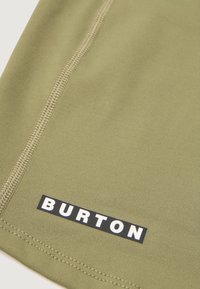 Tkanina w kolorze oliwkowym z prążkowaną strukturą, z czarną prostokątną metką z białym napisem "BURTON" w dolnym rogu.