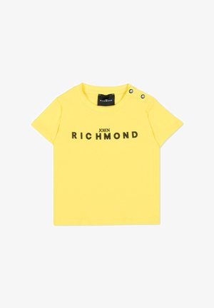 Żółta koszulka dla małego dziecka z krótkim rękawem, z czarnym napisem "JOHN RICHMOND" na przodzie oraz dwoma czarnymi zatrzaskami na lewym ramieniu.