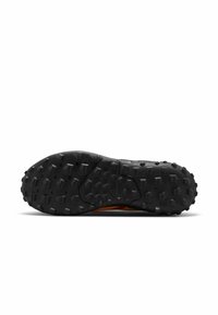 Suola di scarpa sportiva nera con un motivo testurizzato e a chiodi per la trazione, con un accento arancione visibile lungo il lato.