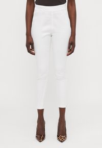 White high-waisted pants with a slim fit, featuring a smooth texture and cropped length, paired with pointed leopard print heels.