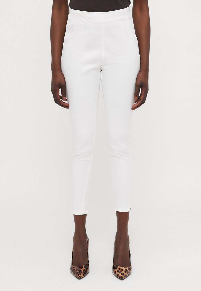 White high-waisted pants with a slim fit, featuring a smooth texture and cropped length, paired with pointed leopard print heels.