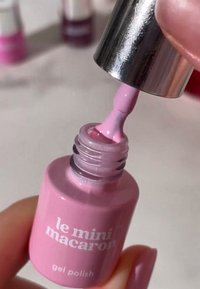 Różowy lakier żelowy w cylindrycznej butelce z metalową nakrętką. Etykieta z napisem "le mini macaron" w bieli. Pędzelek pokryty lakierem.