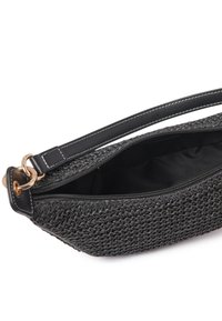 Svart flettet håndveske med textured ytre, detaljer i gulltone, toppåpning med glidelås og en glatt lærrem med hvite sømmer.