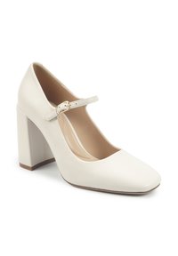 Chaussure à talon bloc en cuir blanc avec un bout carré et une fine sangle réglable autour de la cheville, dotée d'une accent en boucle dorée.