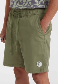 Olive green shorts with an elastic waistband and drawstring, featuring side pockets and a round logo patch on the lower left leg.