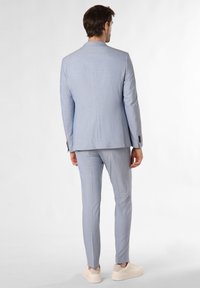 Light blue suit with a tailored fit, single vent, and long sleeves, paired with beige sneakers. Minimalist design with no patterns.