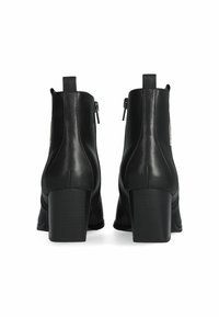Stivaletti neri in pelle con gambale curvo, tacco piatto, due cerniere laterali e una linguetta sul retro. Texture liscia e finitura lucida.