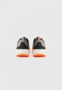Black and gray athletic shoes with a textured mesh upper, orange accents, and a white outsole featuring a patterned grip.