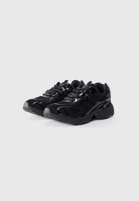Schwarze Sportschuhe mit einem Obermaterial aus Mesh und Synthetik, strukturierten Gummisohlen, abgerundeter Spitze und kontrastierenden grauen Akzenten.