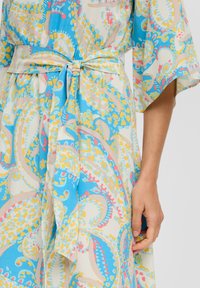 Lichte, gestreepte jurk met een blauw, geel en roze paisley ontwerp, voorzien van een strik in de taille en wijde mouwen.