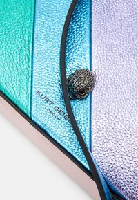 Struktureret clutch med paneler i aqua, blå og lilla, med sort kant og sølvfarvet håndformet lukning. Brandlogo synligt.