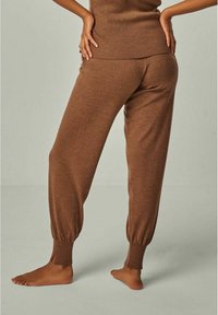 Brown knit sweatpants with a tapered leg, ribbed cuffs, and a soft texture. Styled with a matching brown top.