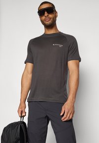 Schwarzes Sport-T-Shirt mit kurzen Ärmeln aus leichtem Stoff, das ein kleines Logo auf der Brust und einen entspannten Schnitt aufweist.