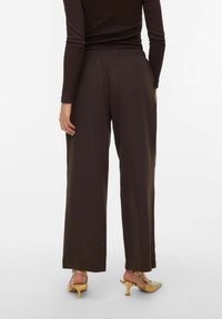 Pantalon large marron avec une taille élastique, une texture lisse et une coupe décontractée. Fini avec un design simple et sans motifs visibles.