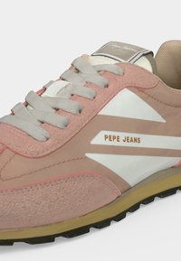 Κοντινό πλάνο ενός ροζ και μπεζ sneaker Pepe Jeans με μπεζ κορδόνια και λευκές λογότυπες λεπτομέρειες σε μαύρη και καφέ σόλα.