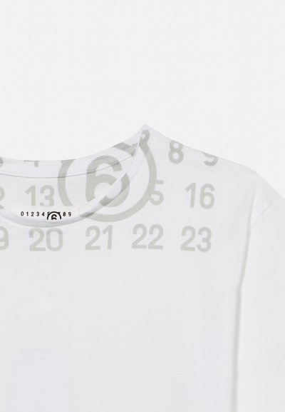 Fehér kerek nyakú póló világosszürke számmal és a nyakkivágásnál egy körbe foglalt hatos számmal.