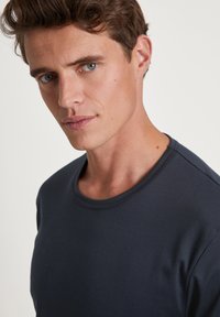 Navy blue crew neck t-shirt made of soft fabric, featuring a smooth texture and a fitted design, displaying minimal stitching details.