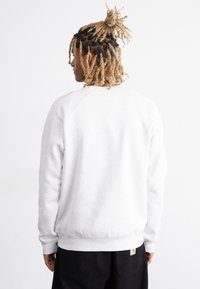 Grå sweatshirt med rund hals, ribbede manchetter og kant. Fremstillet af blødt stof, har en lille logotag på den nederste ryg.