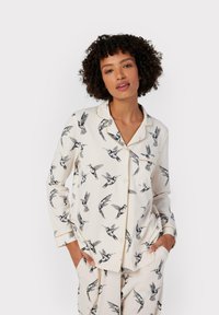 White pajama set featuring a hummingbird print in black. The top has long sleeves, a collar, and a button-down front with contrasting trim.