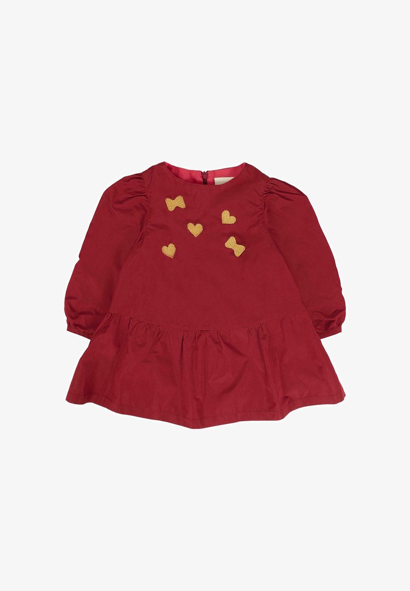 Abito rosso con maniche a sbuffo e gonna arricciata. Presenta ricami dorati a forma di cuore e fiocco sul davanti. Chiusura con cerniera sul retro. Materiale in cotone.