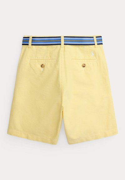 Κίτρινα σορτς με κουμπωτές τσέπες στο πίσω μέρος και ζώνη με ρίγες σε μπλε, λευκό και μαύρο χρώμα σε απλό φόντο.