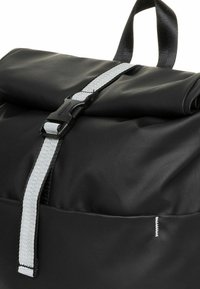 Zwarte rolltop-rugzak gemaakt van gestructureerd, duurzaam materiaal. Voorzien van een grijze verstelbare riem met een kunststof gesp en een enkele bovenste handgreep.