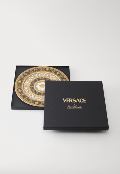 Χρυσό και λευκό διακοσμητικό πιάτο σε μαύρο κουτί Versace, με περίτεχνα σχέδια και κεντρικό σχεδιασμό με μετάλιο. Το κουτί φέρει την ετικέτα Versace.