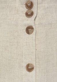 Linen fabric in beige with a textured finish, featuring four round brown buttons with swirled patterns.