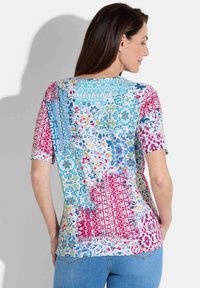 Chemise à manches courtes avec un motif floral et géométrique multicolore. Dotée d'un col rond et d'une coupe ample, fabriquée en tissu léger.
