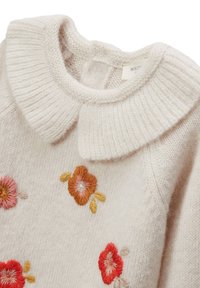Pull en maille beige clair avec un col épais à côtes. Présente des fleurs colorées brodées en rose, orange et rouge sur le devant.