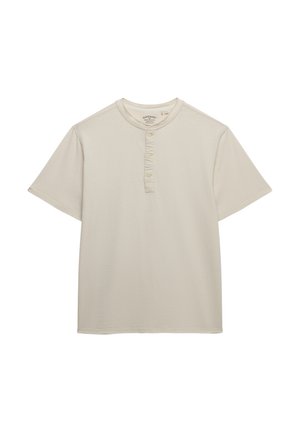 Beiges Henley-Shirt mit kurzen Ärmeln, drei Knöpfen und einem dezenten eingestickten Logo auf der Brust vor weißem Hintergrund.