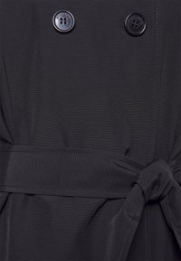 Tissu de trench-coat noir avec nervures verticales, double rangée de boutons et ceinture à nouer. Texture lisse avec un design épuré.