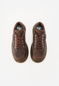 Scarpe in pelle marrone con finitura texturizzata, punta tonda e cuciture gialle a contrasto su una suola nera spessa. Lacci e logo visibili.
