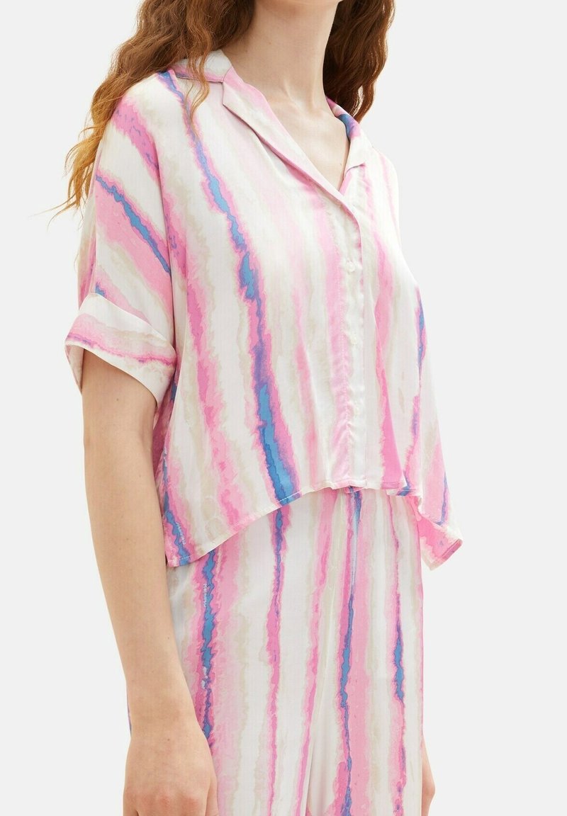 Camicia a maniche corte rosa e bianca con strisce astratte blu e rosa. Tessuto leggero e vestibilità rilassata. Collare rotondo e chiusura frontale con bottoni.
