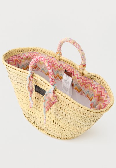 Υφαντό ψάθινο τσάντα ώμου με υφασμάτινη φόδρα σε παστέλ ζιγκ-ζαγκ μοτίβο και ταιριαστά τυλιγμένα χερούλια, όπου διακρίνονται η ετικέτα της μάρκας και η ετικέτα φροντίδας στο εσωτερικό.