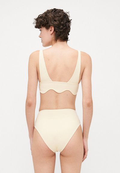 Hellbeige Bikini mit einem gewellten Design auf der Rückseite. Das Oberteil hat breite Träger, und der hochgeschnittene Slip hat eine glatte Textur.