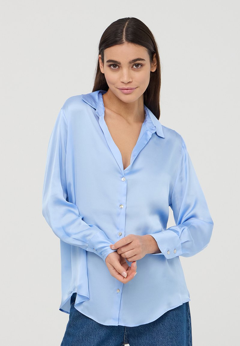 Camicia button-up in satin azzurro chiaro con maniche lunghe, colletto e bottoni lucidi, caratterizzata da una vestibilità comoda e orlo curvo.
